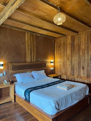 a bedroom with a large bed with wooden walls at Girang Rinjani Bungalows in Tetebatu