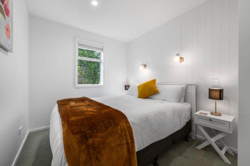 a white bedroom with a bed and a window at Sea-Renity Picton, Apt B in Picton