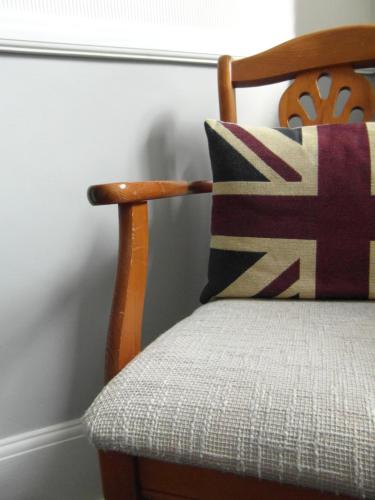 a wooden chair with a pillow on it at Harriet House B&B in Canterbury