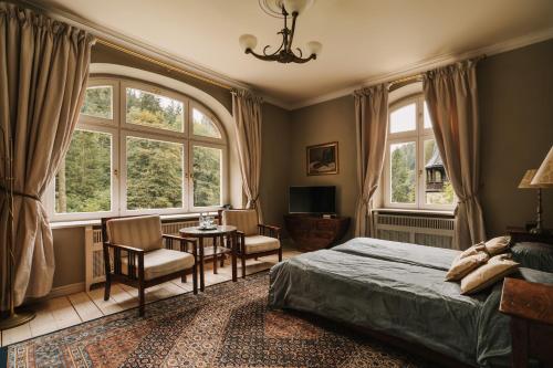 a bedroom with a bed and a table and two windows at Villa Titina in Miedzygorze
