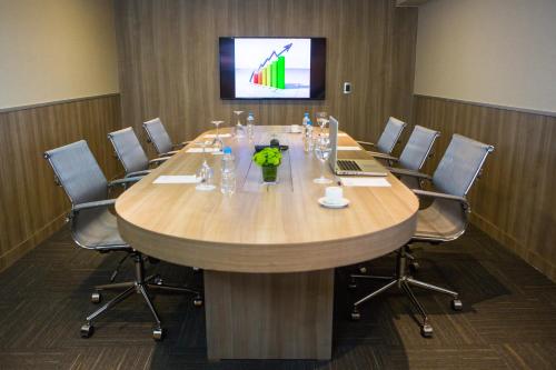 a conference room with a large wooden table with chairs at Novotel RJ Porto Atlantico in Rio de Janeiro