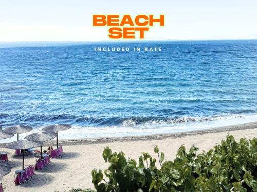 a beach with chairs and umbrellas and the ocean at Aiora Suites in Psakoudia