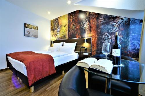 Una habitación de hotel con una cama y una mesa con una botella de vino en Ascot Hotel, en Remscheid