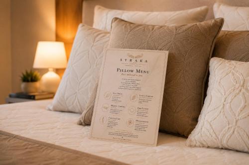 a bed with a phantasy pillow manual on it at Syraka Design Rooms & Suites in Syracuse
