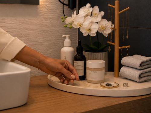 a person holding a hand on a counter with cosmetics at Syraka Design Rooms & Suites in Syracuse