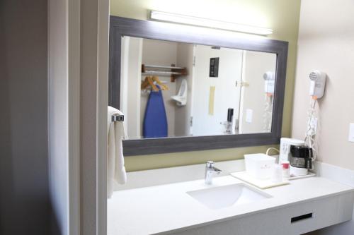 a bathroom with a sink and a large mirror at Baymont by Wyndham Plano in Plano