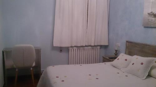 a bedroom with a bed with white sheets and a window at Hospedaje A Goleta in O Barqueiro