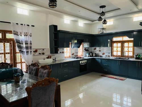 a large kitchen with black cabinets and a table at MTR Guesthouse in Jaffna