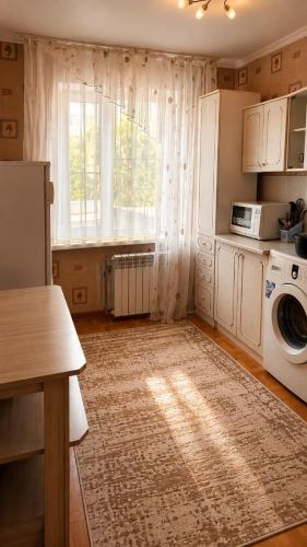 a kitchen with a washing machine and a window at Economy - class apartment in Pavlodar
