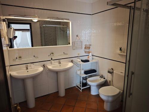 a bathroom with two sinks and a toilet and a mirror at Casa Luz in Hermigua