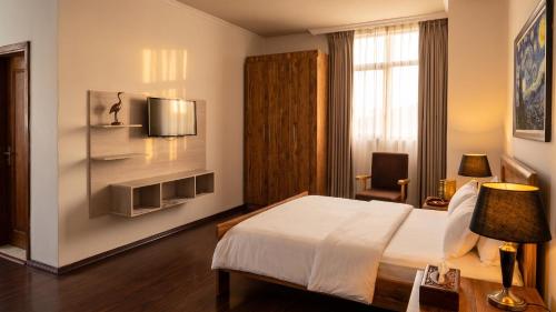 a bedroom with a bed and a tv on a wall at Victoria Hotel Apartment in Addis Ababa