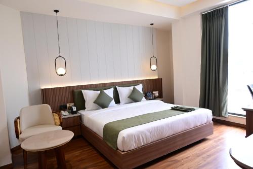 a bedroom with a large bed and a chair at Trevon Hotel Gujrat Centrale, Ranchi in Rānchī