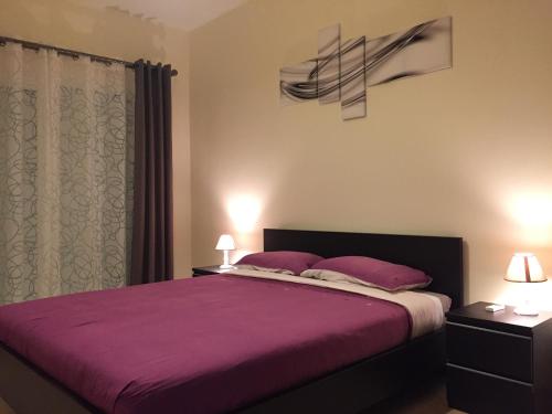 a bedroom with a large bed with purple sheets and pillows at Appartement Saidia Méditerranée in Saïdia