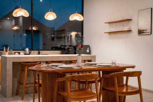 a wooden table with chairs and a counter in a kitchen at Snuggy Shack Villas in Munggu