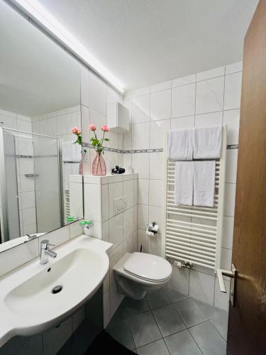 a white bathroom with a toilet and a sink at Gästehaus Huber - Hotel Garni in Bad Füssing