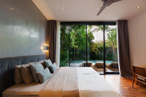 a bedroom with a large bed and a large window at Villa Pakuk by Alfred in Bali in Canggu