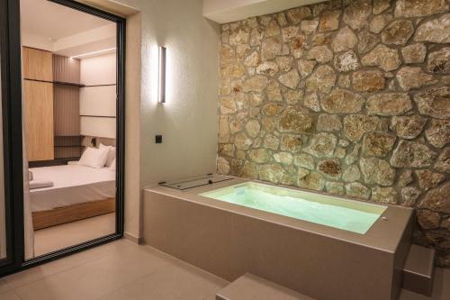 a bathroom with a tub with a stone wall at Sophe Boutique Stay 2 in Kallithea Halkidikis