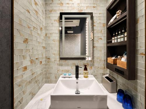 a bathroom with a white sink and a mirror at Hotel BaliBali 仙台 in Kōtōdaitōri