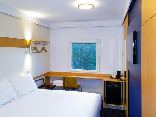 a room with a bed and a desk and a window at ibis Budget - Gosford in Gosford