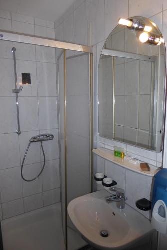 a white bathroom with a shower and a sink at Hotel Ring Park in Buchen