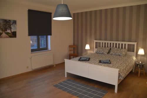 een slaapkamer met een wit bed en een televisie bij De Staberg in Bilzen