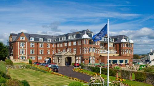 a large brick building with a flag in front of it at The Victoria Hotel & Source Spa in Sidmouth