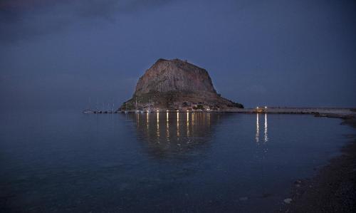 a large rock in the middle of the water at night at Filoxenia Hotel Monemvasia in Monemvasia