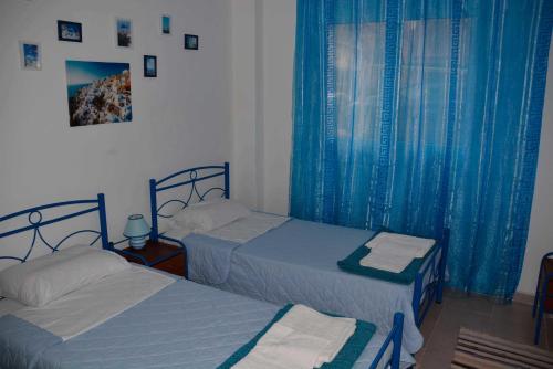 アテネにあるCosy Apartment Pinotsiの青いカーテン付きのベッドルームのベッド2台