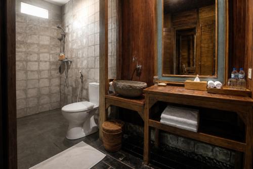 a bathroom with a sink and a toilet and a mirror at The Campuhan Retreat in Munggu