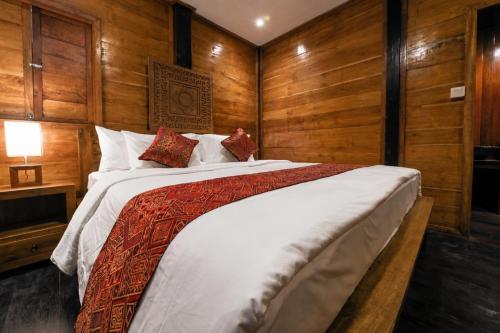 a bedroom with a large bed with wooden walls at The Campuhan Retreat in Munggu