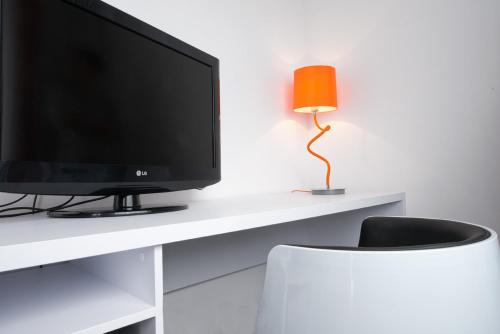 a television sitting on a white desk with a lamp at Wyndham Garden Düsseldorf City Centre Königsallee in Düsseldorf
