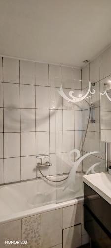 a white bathroom with a tub and a sink at Gîte fabuleux, jardin, terrasse, parking in Saint-Vincent-de-Mercuze
