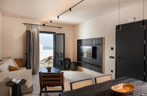 a living room with a table and a couch and a television at Avento Luxury Suites in Santorini