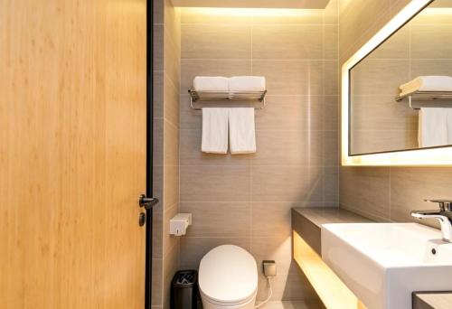 a bathroom with a sink and a toilet and a mirror at JI Hotel Shanghai Stadium in Shanghai