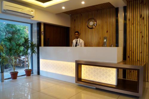 a man standing behind a counter in a lobby at Hotel Midtown in Vadodara
