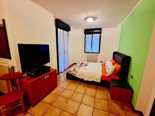 a bedroom with a bed and a flat screen tv at Bernina Stop & Go apartment - 30 steps to the red train in Tirano