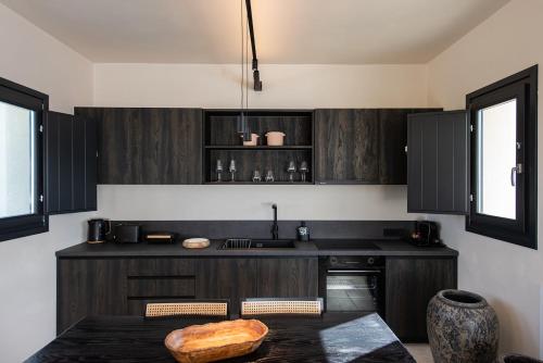 a kitchen with black cabinets and a table at Avento Luxury Suites in Santorini