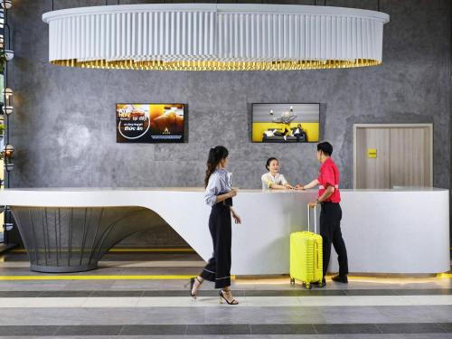 a group of people standing at a counter at an airport at ibis Styles Vung Tau in Vung Tau