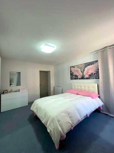 a bedroom with a large white bed with pink pillows at La Cascata in Valbrenta 