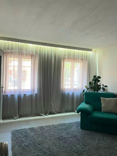 a living room with a green couch and two windows at La Cascata in Valbrenta 