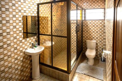a bathroom with a shower and a toilet and a sink at Aniyak Guest House in Sekondi-Takoradi