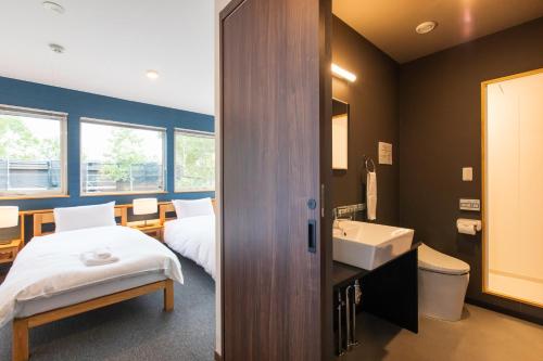 a hotel room with a bed and a sink and a bathroom at Hirafu Tomten in Kutchan