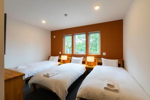 a room with three beds and two windows at Hirafu Tomten in Kutchan