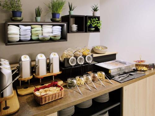 a kitchen with a counter with plates and dishes at Aparthotel Adagio Access Freiburg in Freiburg im Breisgau