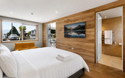 a bedroom with a large white bed and wooden walls at Alp Studios Apartment 1 in Wanaka