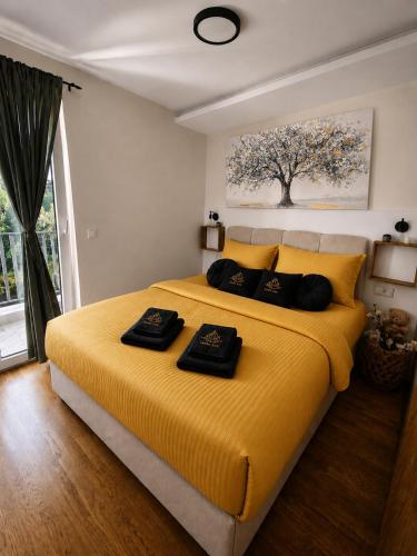 a bedroom with a large yellow bed with black towels on it at Lenka Lux Apartmans in Divčibare
