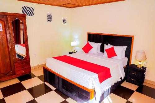 a bedroom with a large bed with red pillows at Martin Aviator Hotel in Kigali