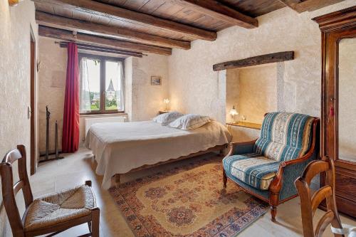 a bedroom with a bed and a chair and a window at B&B La Demoiselle in Aignay-le-Duc