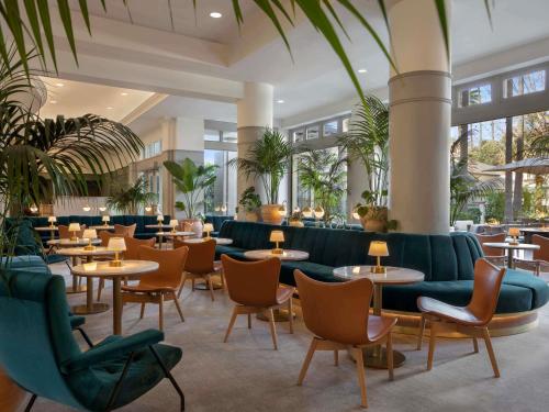 a restaurant with couches and tables and chairs at Fairmont Miramar Hotel & Bungalows in Los Angeles
