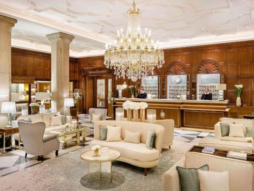 a living room with a chandelier and a salon at Fairmont Hotel Vier Jahreszeiten in Hamburg